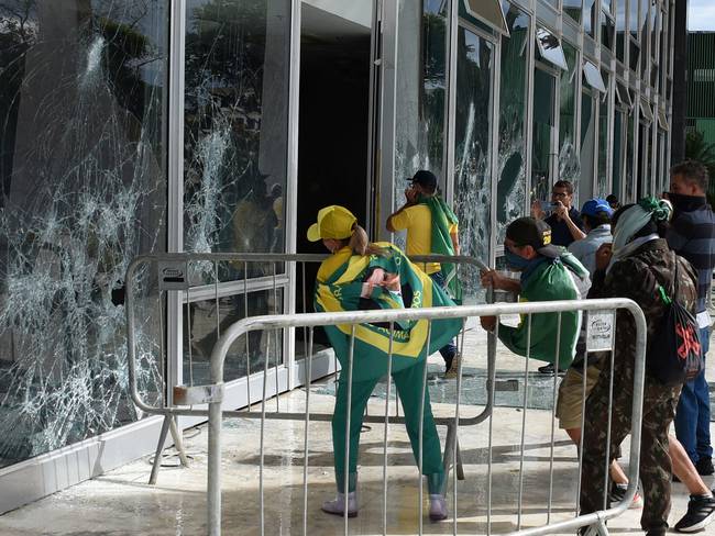 Partidarios del expresidente brasileño Jair Bolsonaro destruyen una ventana del pleno de la Corte Suprema en Brasilia el 8 de enero de 2023. Foto de TON MOLINA/AFP vía Getty Images.