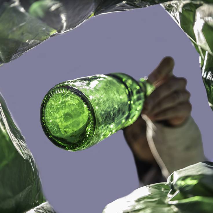 Persona tirando una botella de vidrio a la basura (Foto vía Getty Images)
