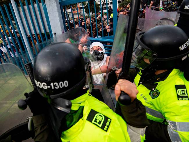 TOPSHOT - An activist argues with riot police during a protest called by feminist groups to denounce an alleged rape of a girl by a doctor in a private clinic and against police brutality in  Bogota on September 10, 2020. (Photo by Juan BARRETO / AFP) (Photo by JUAN BARRETO/AFP via Getty Images)
